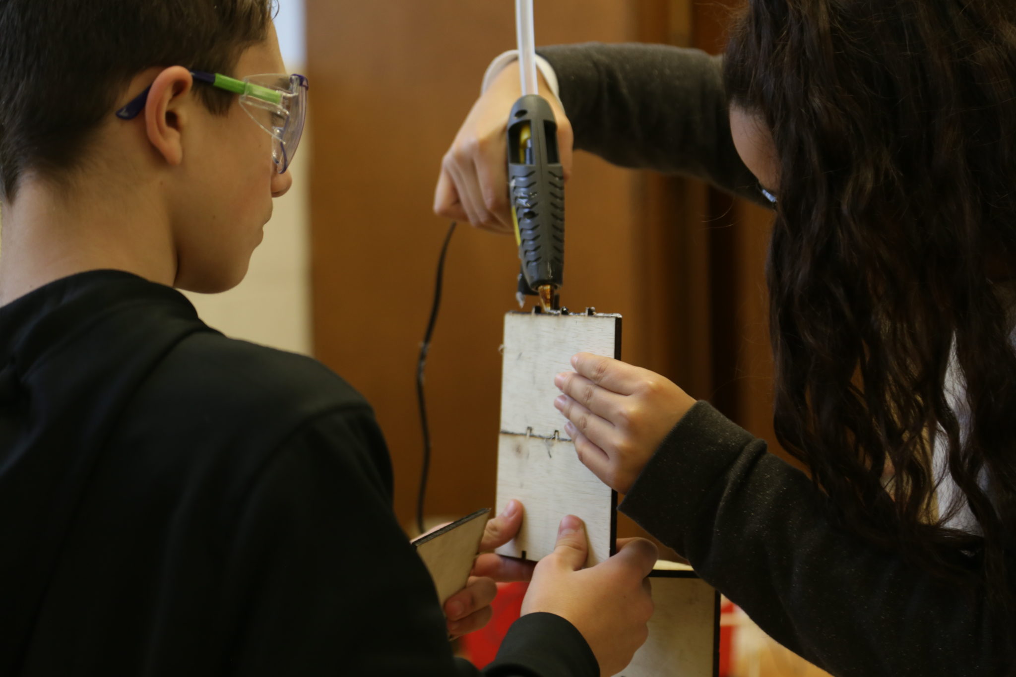 students hot gluing a project together