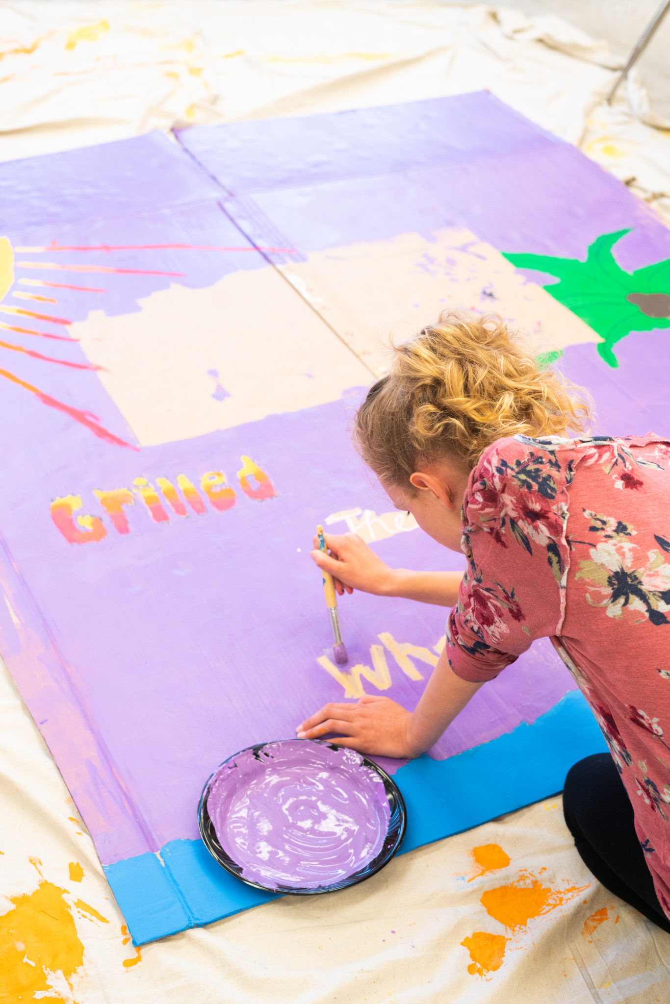 student painting banner on ground