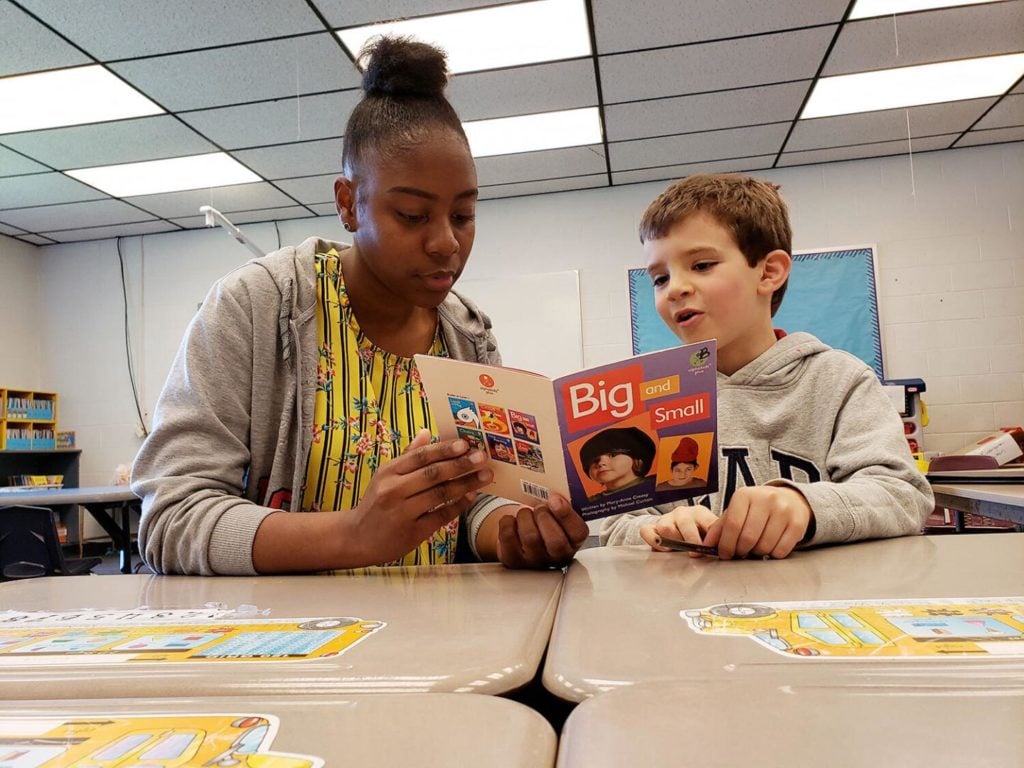 Carol helps 6-year-old native Spanish speaker Bernat Gasch read a book in English.