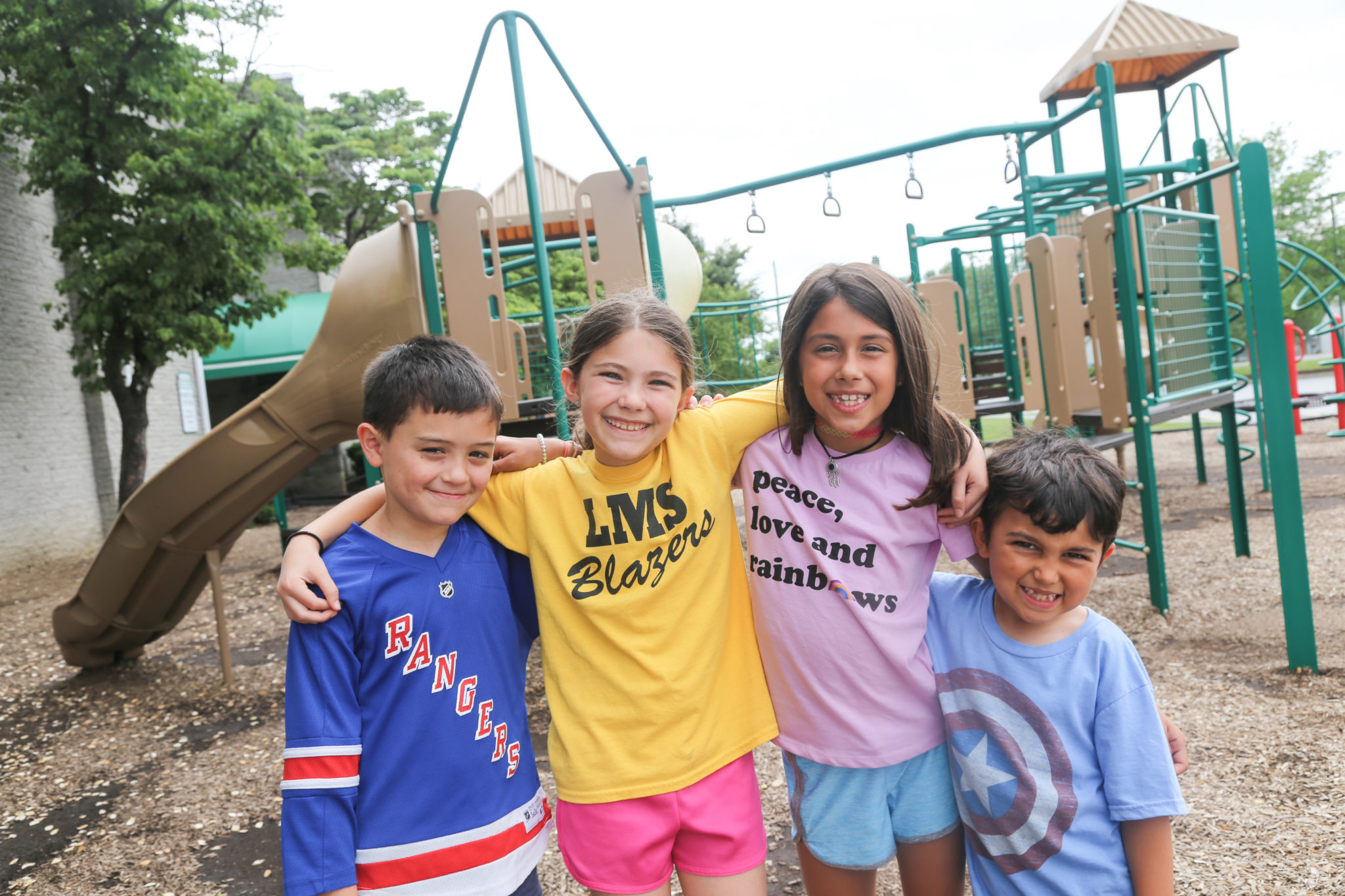 students standing in front of playground smiling