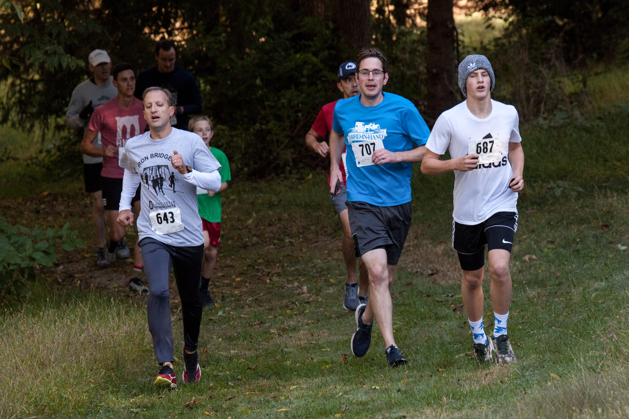 Participants running during the Iron Bridge 5k run through woods and fields