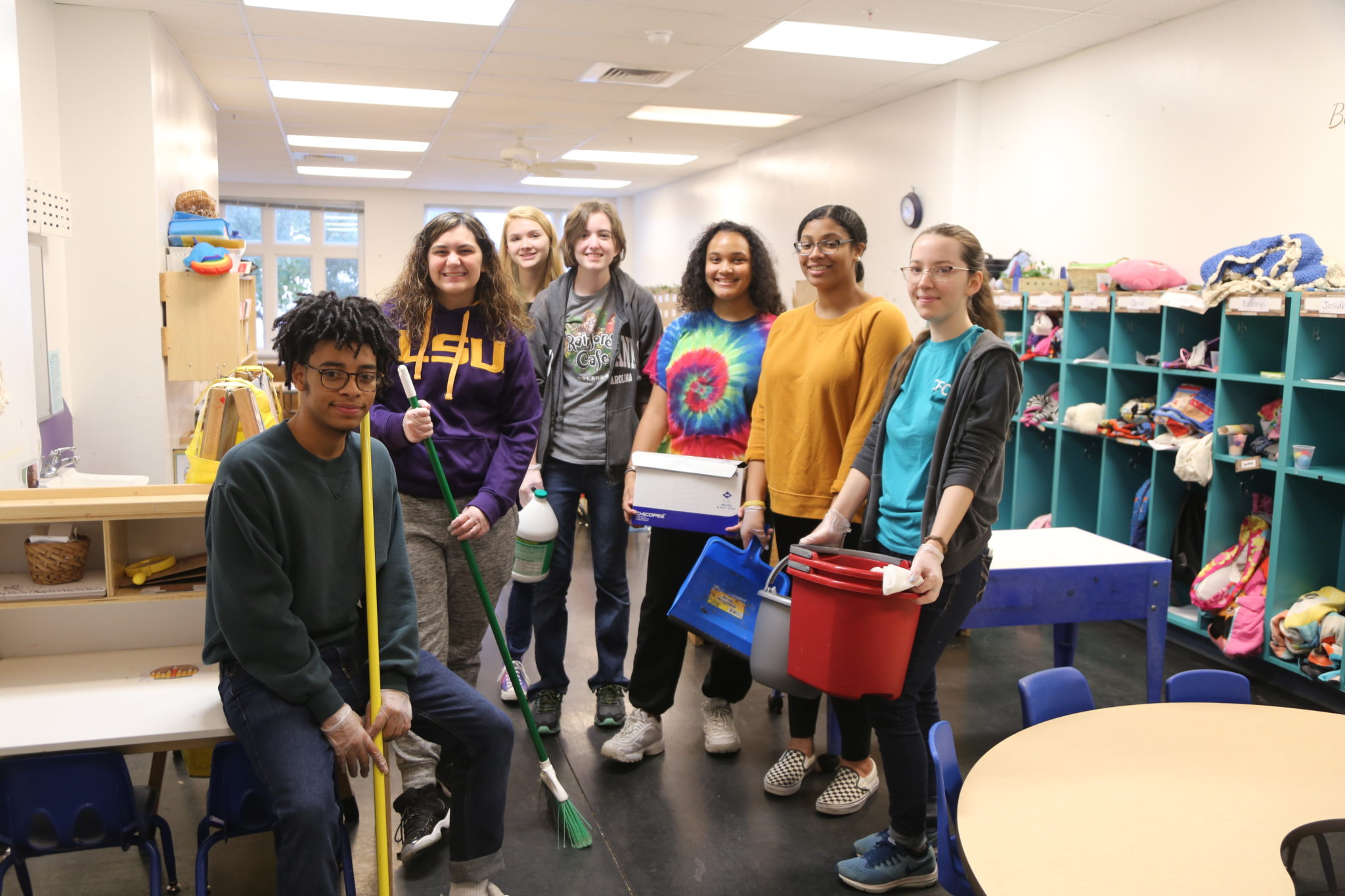 students holding cleaning supplies