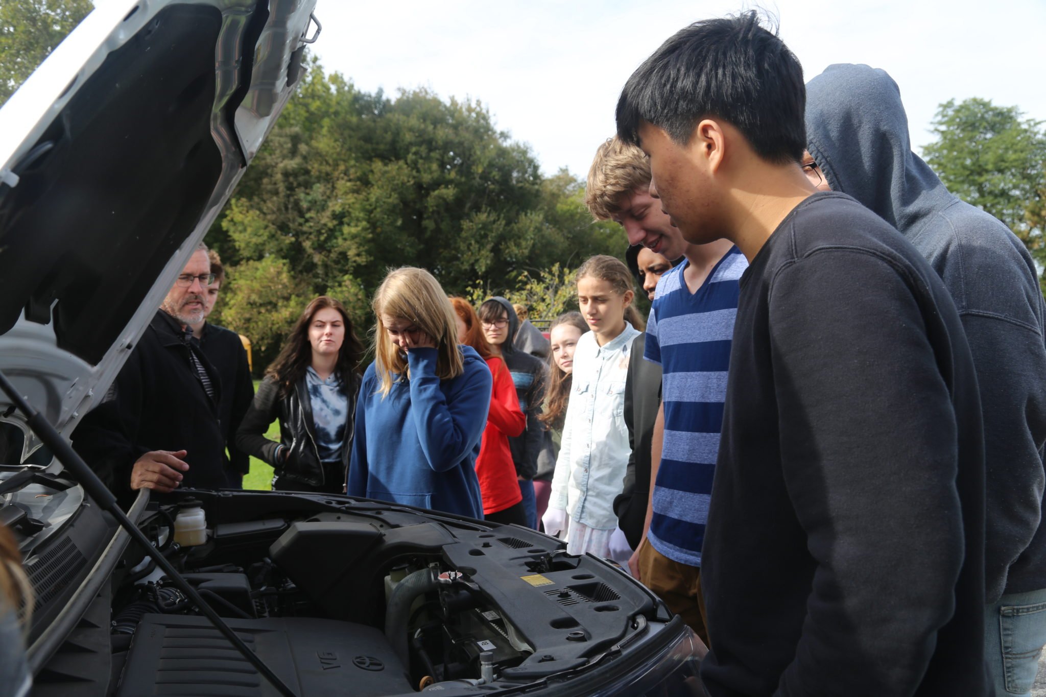 Students inspecting engine of a car