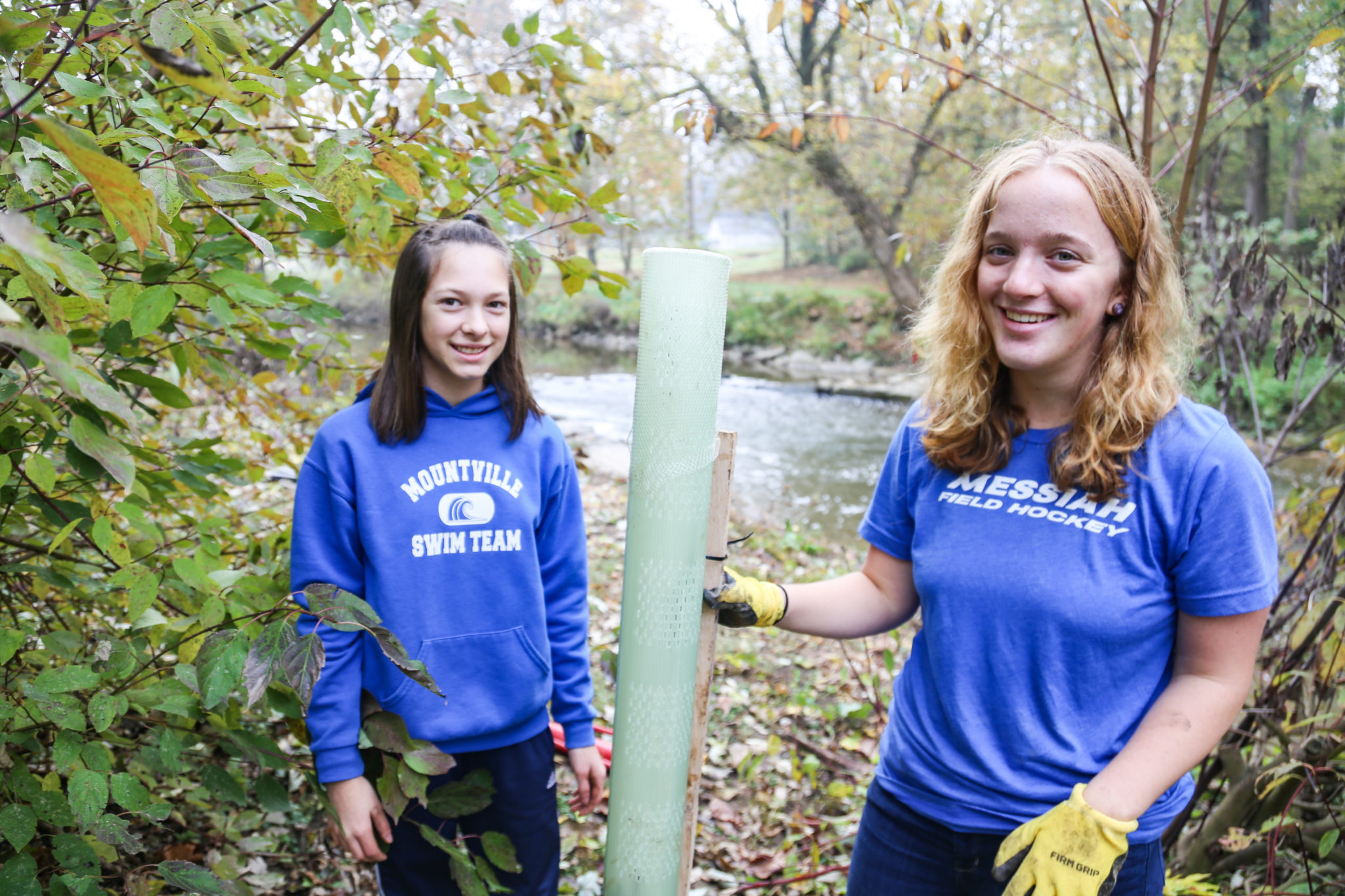 student planting trees on mill stream