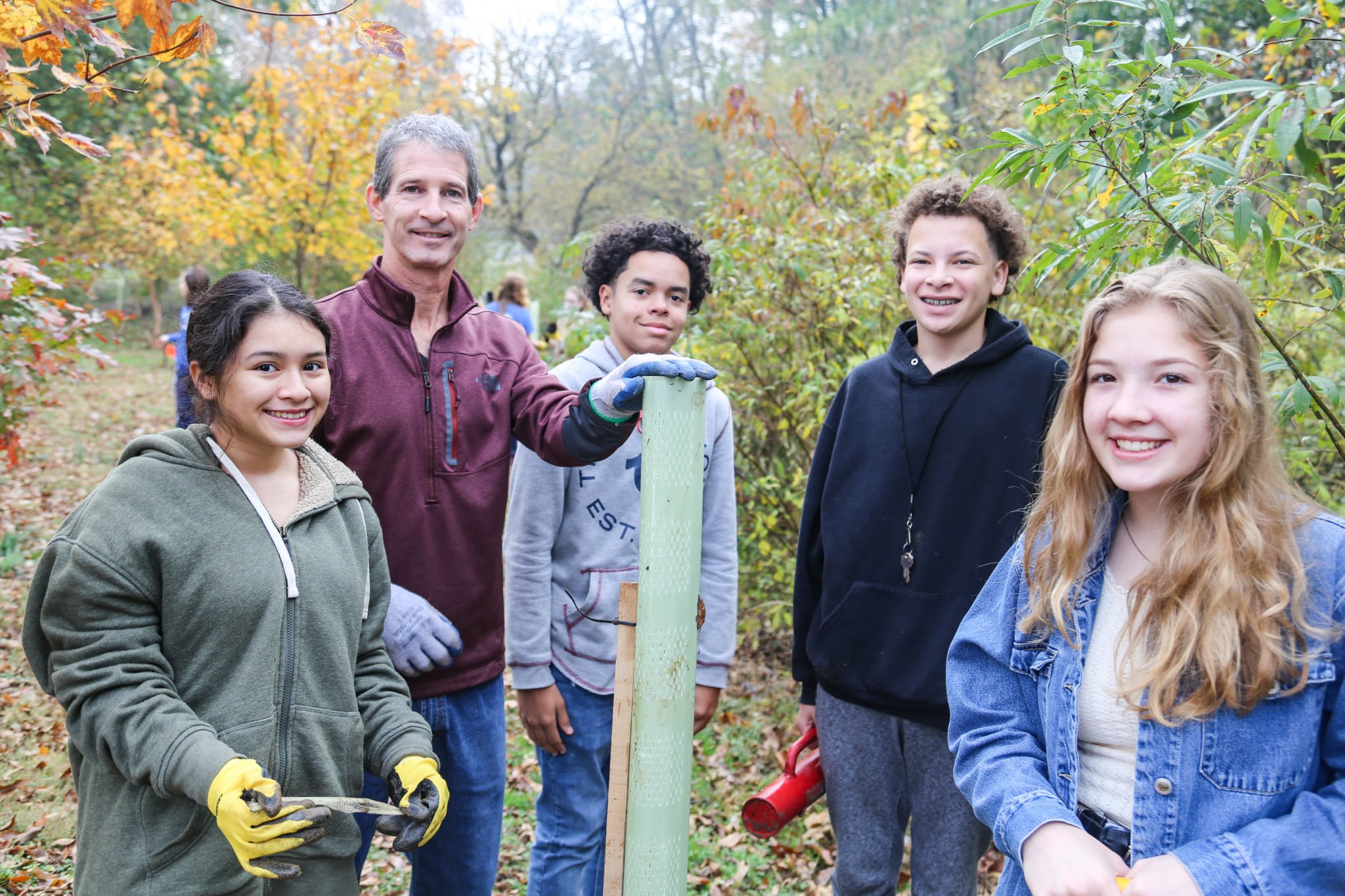 student planting trees on mill stream