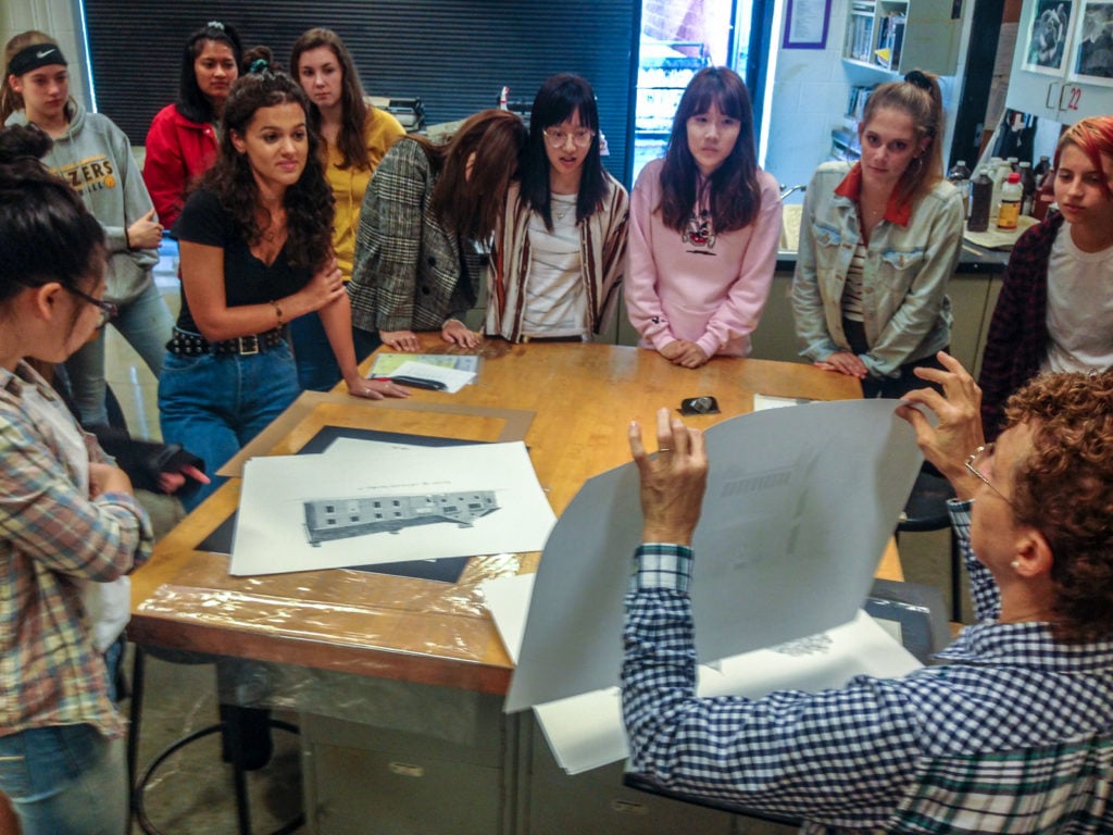 Students standing around table looking at blue prints