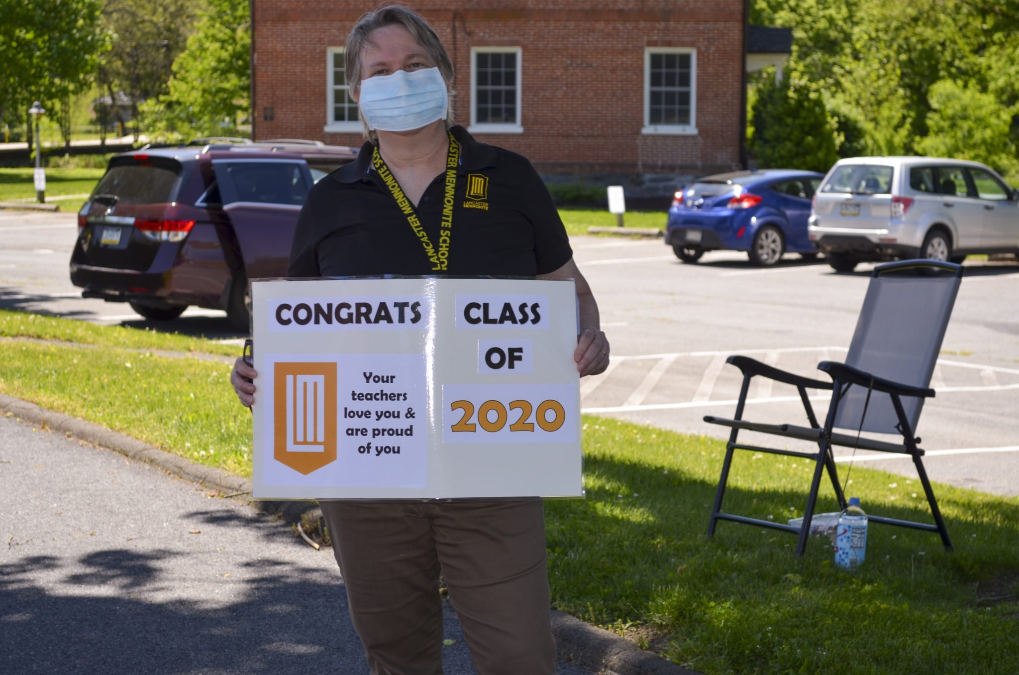 teacher holding congratulation sign for graduates