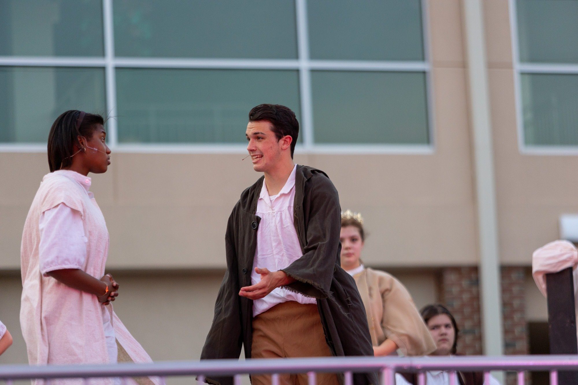 student smiling during the performance of all the worlds a stage