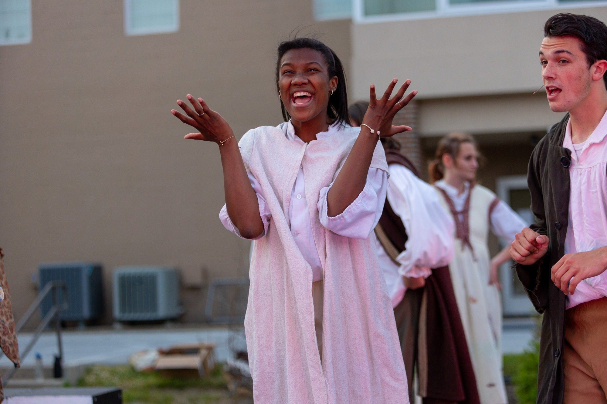 student smiling during the performance of all the worlds a stage