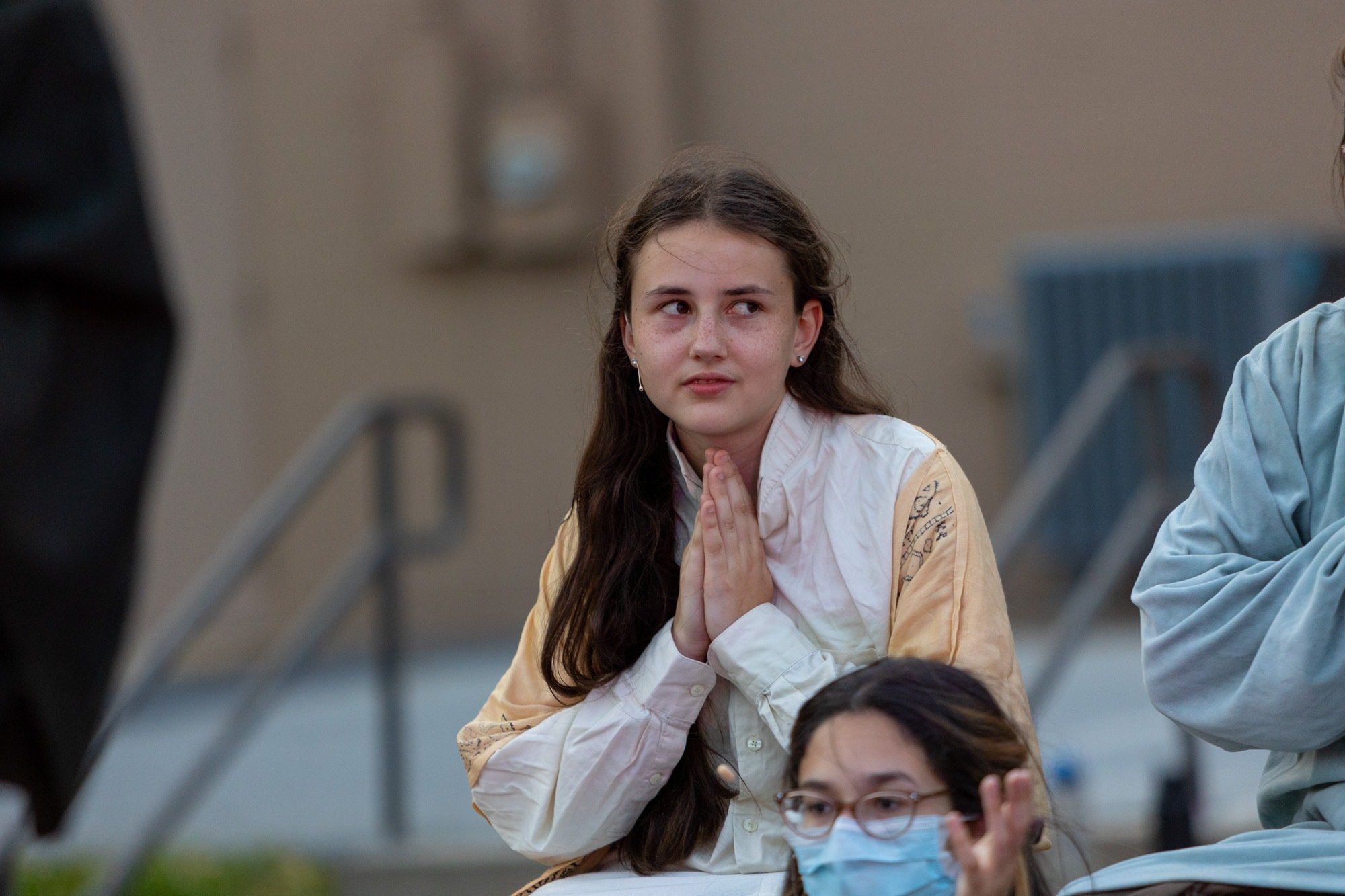 student praying during the performance of all the worlds a stage