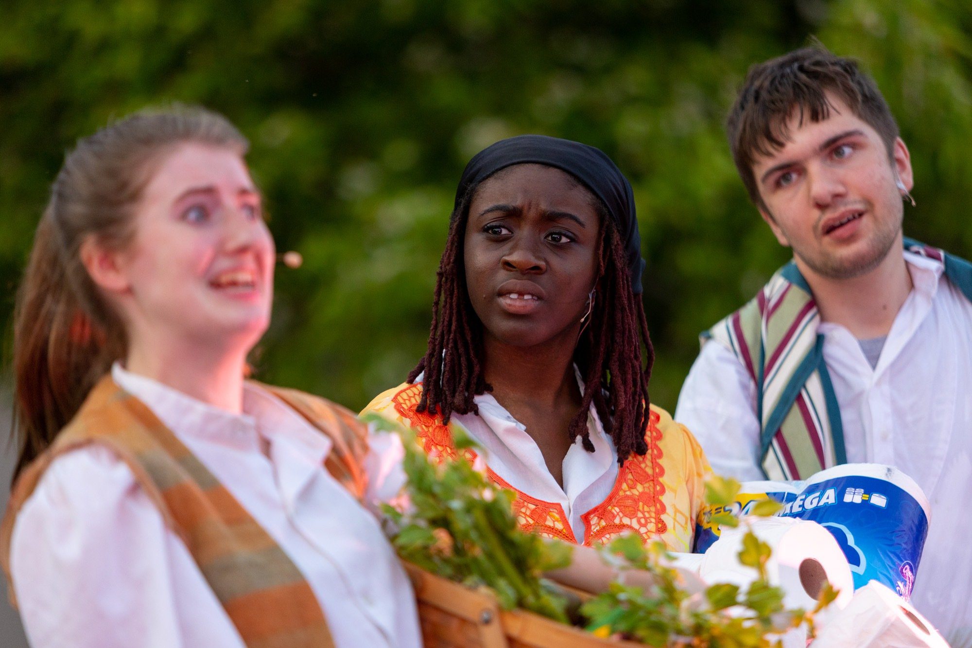 3 student smiling during the performance of all the worlds a stage