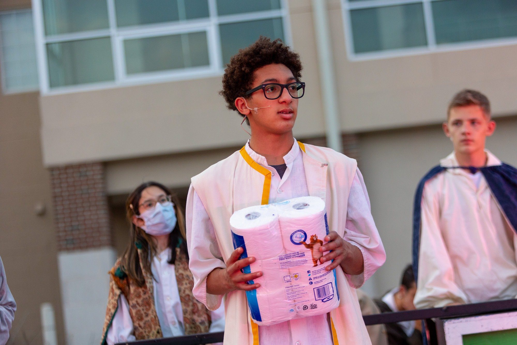 student smiling during the performance of all the worlds a stage