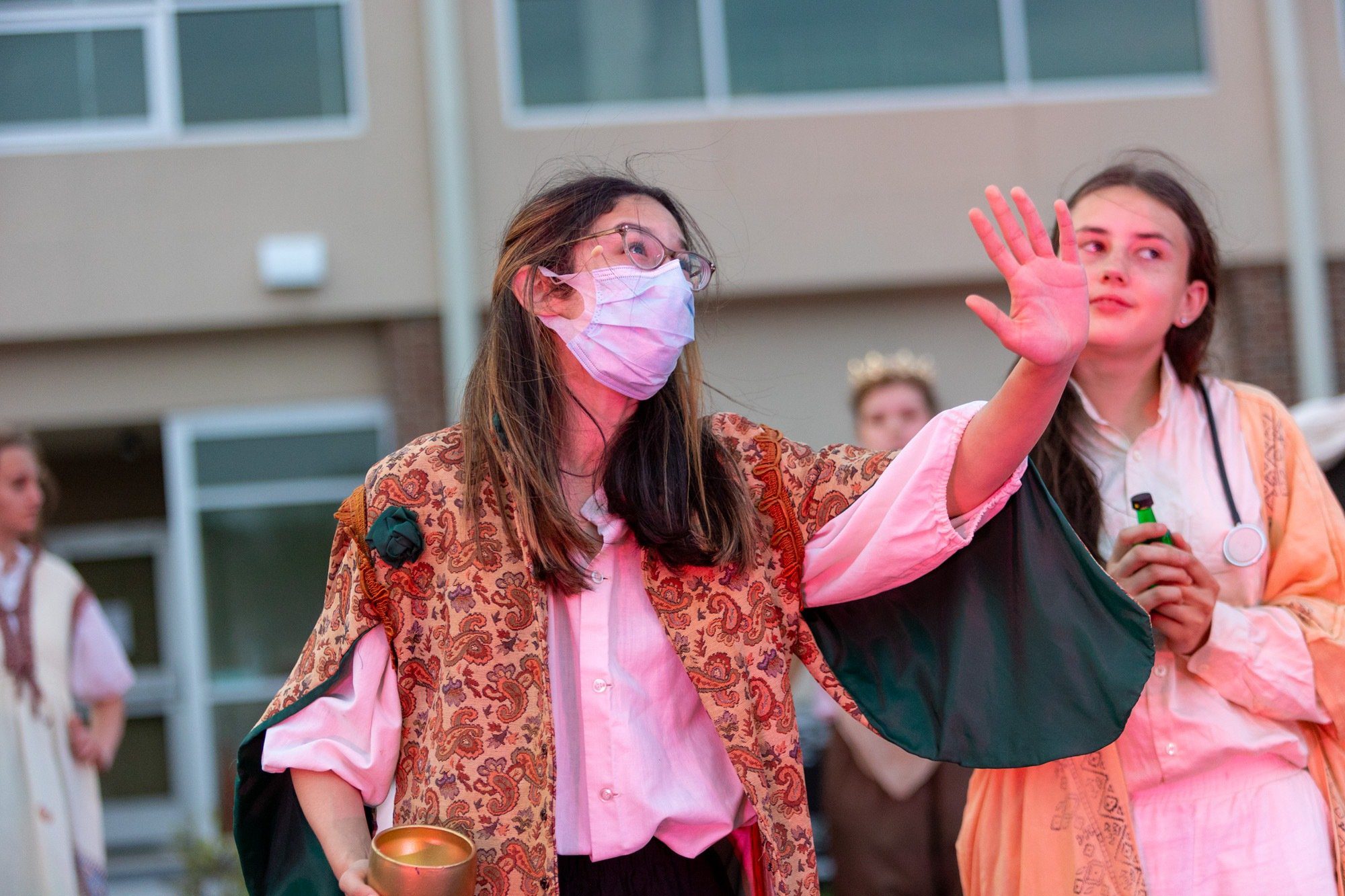 student smiling during the performance of all the worlds a stage