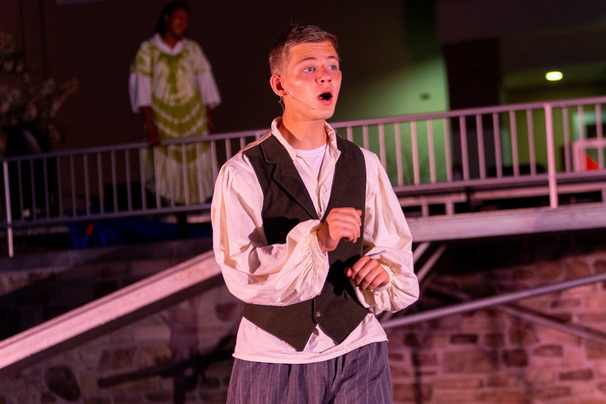 student smiling during the performance of all the worlds a stage