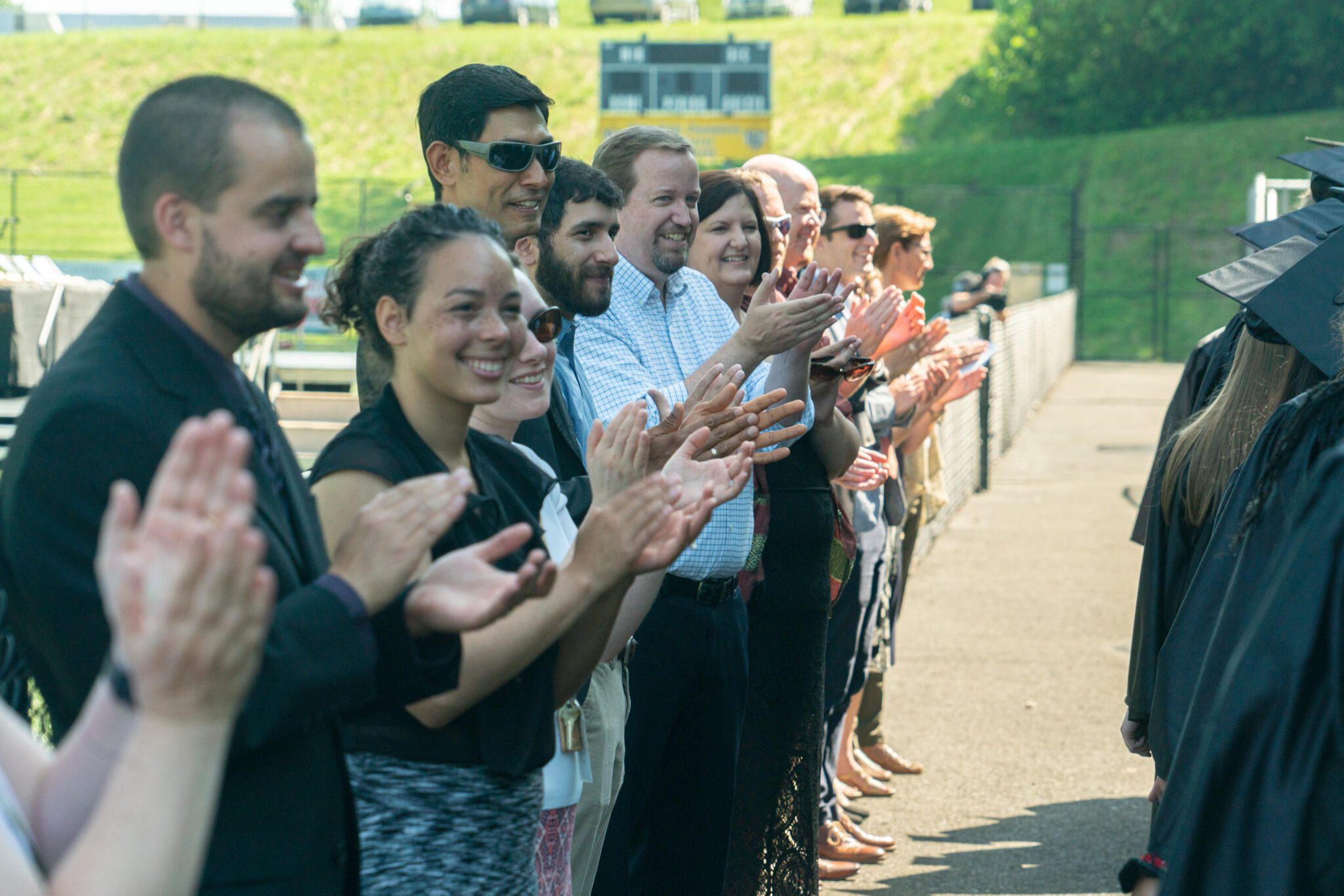 teachers cheering on graduates walking into commencement
