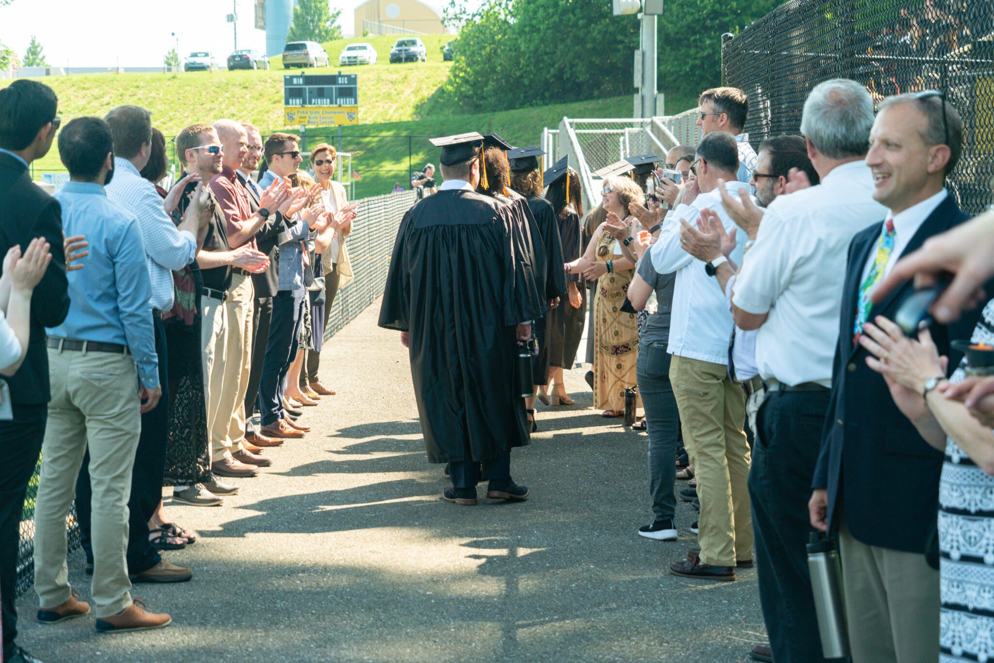 graduates walking into commencement in tunnel of teachers
