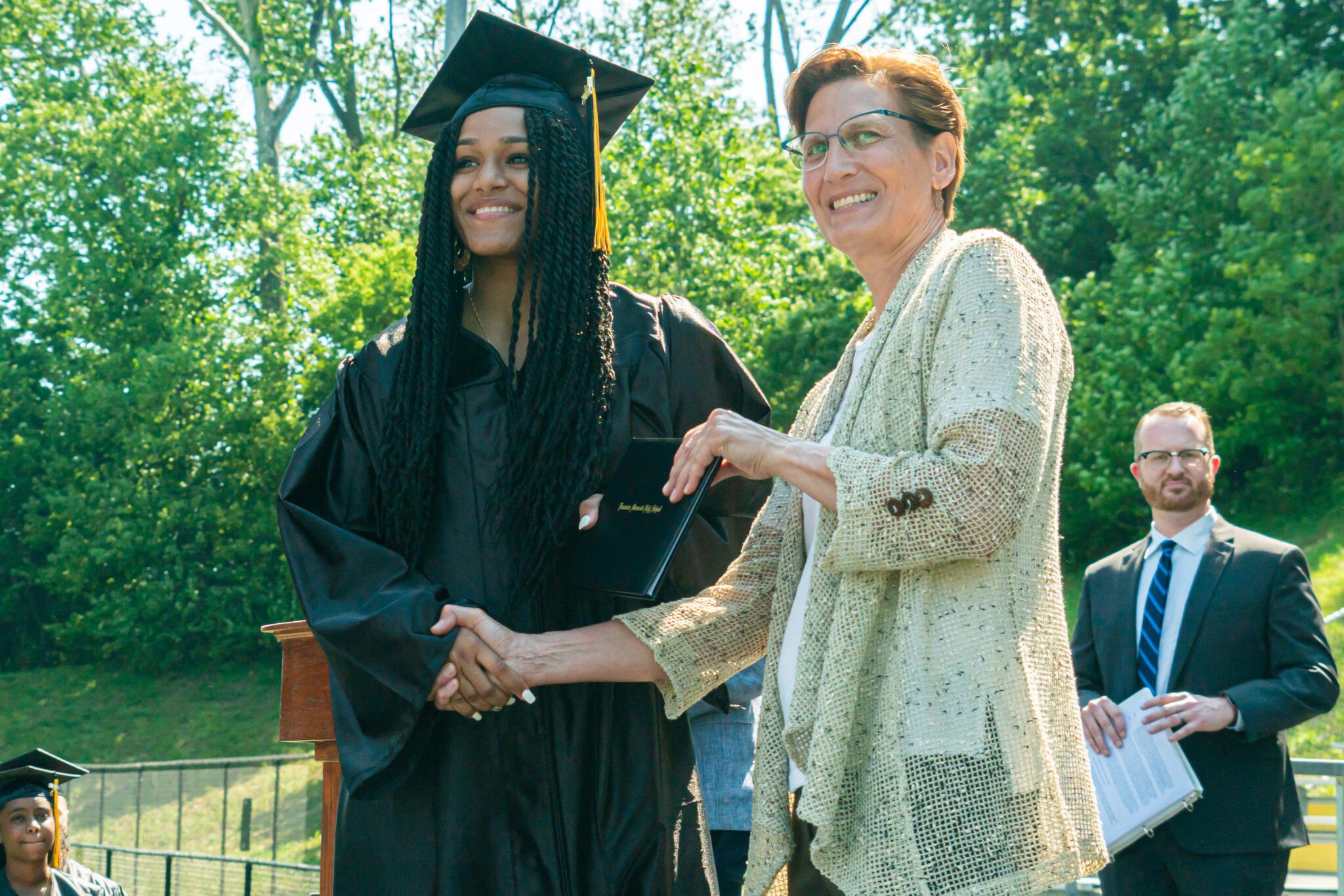 Superintendent gives diploma and shakes hand of student graduate
