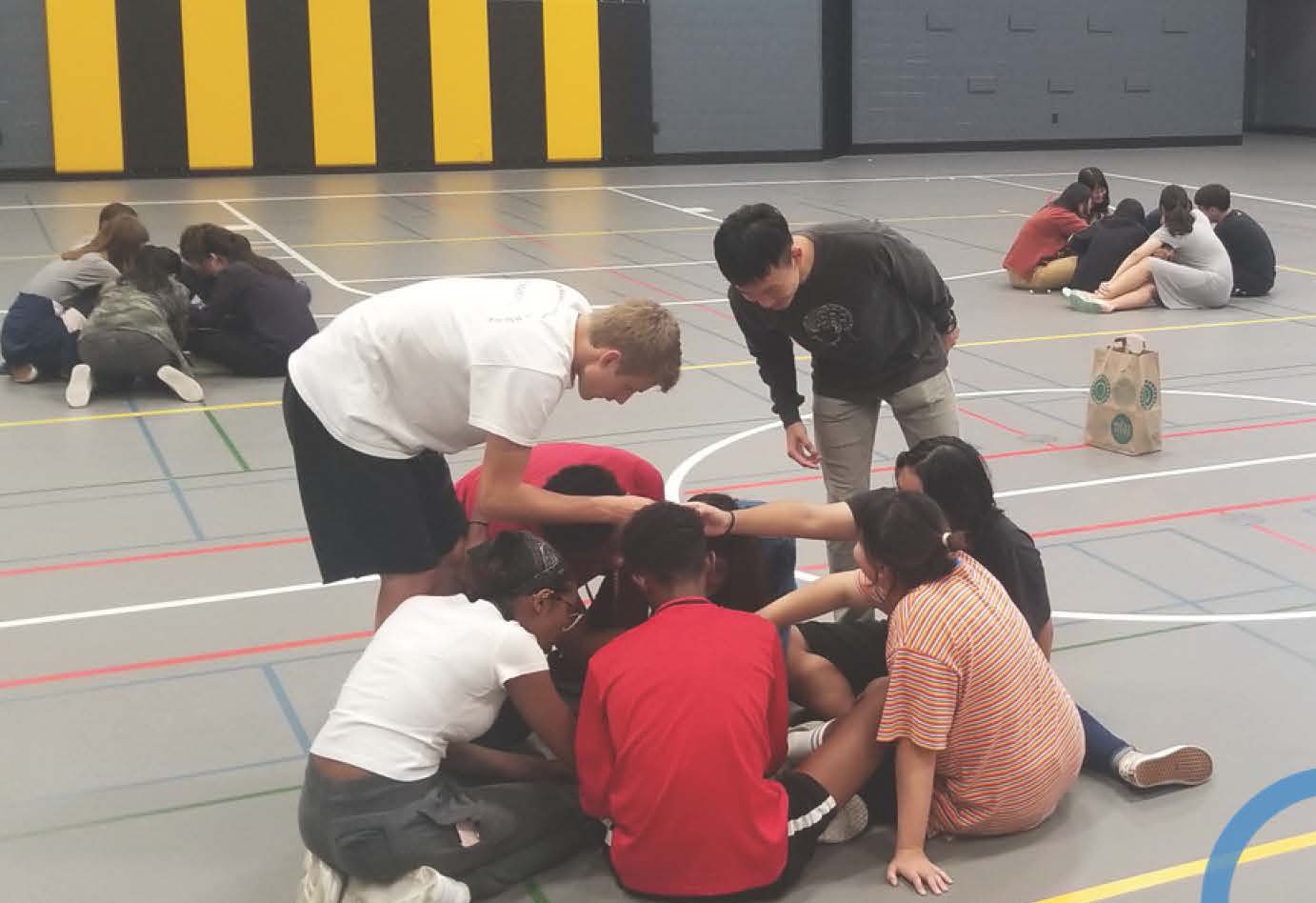 students in the gym doing an activity sitting in a circle