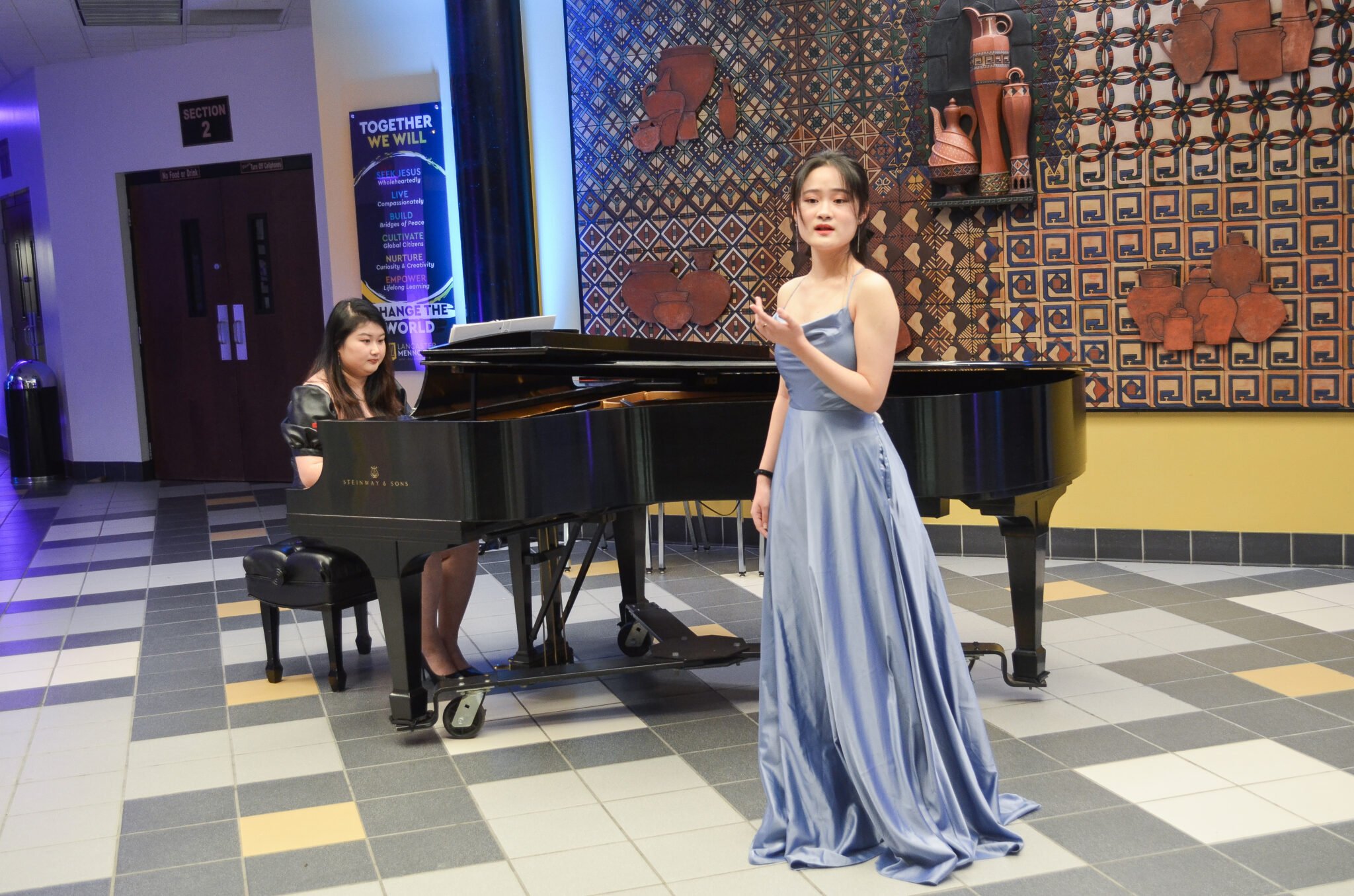 young woman in gown singing with pianist at grand piano