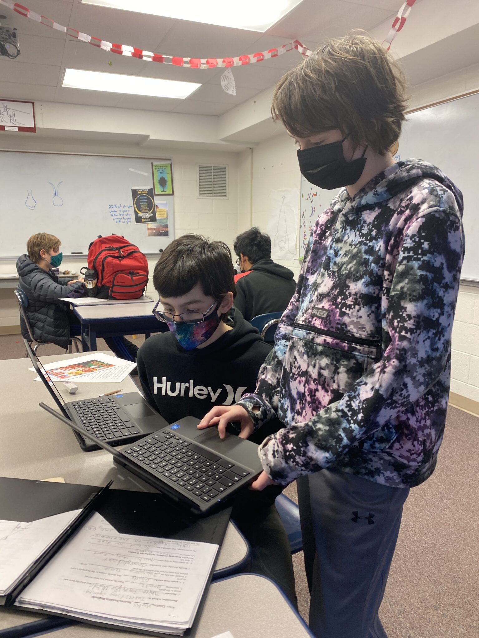 Two students on laptops working on project