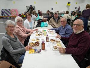 People sitting down enjoying BBQ