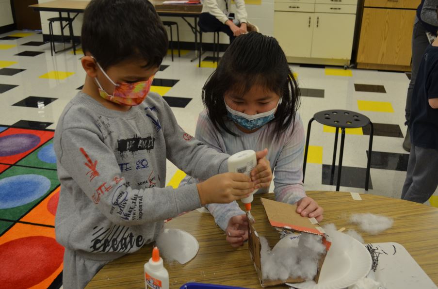 two students glue cardboard