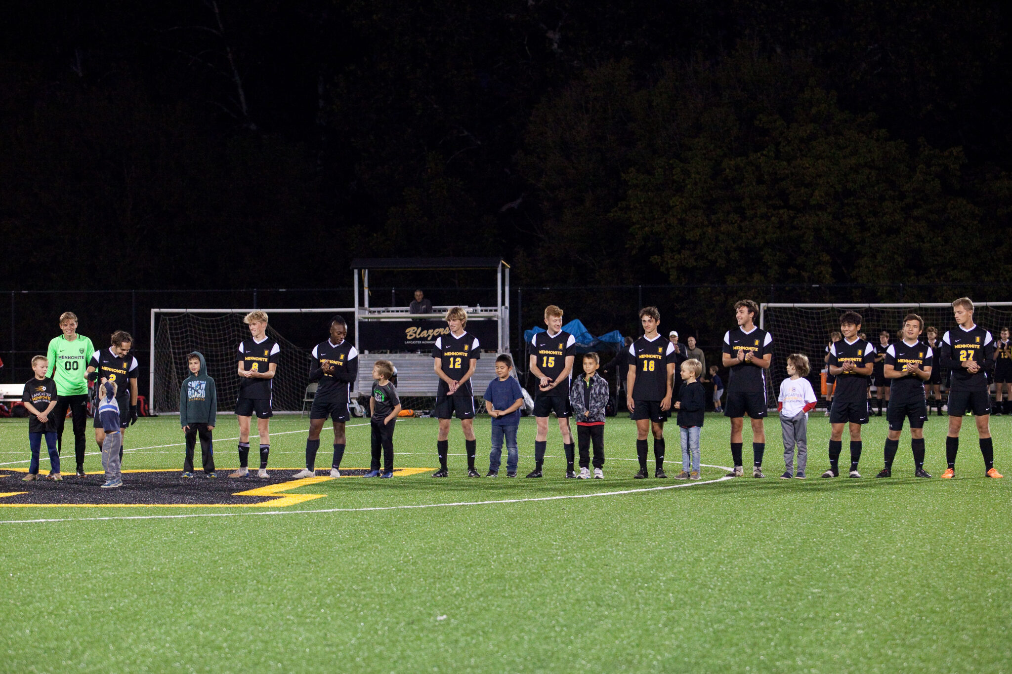 Soccer team and younger students on the field