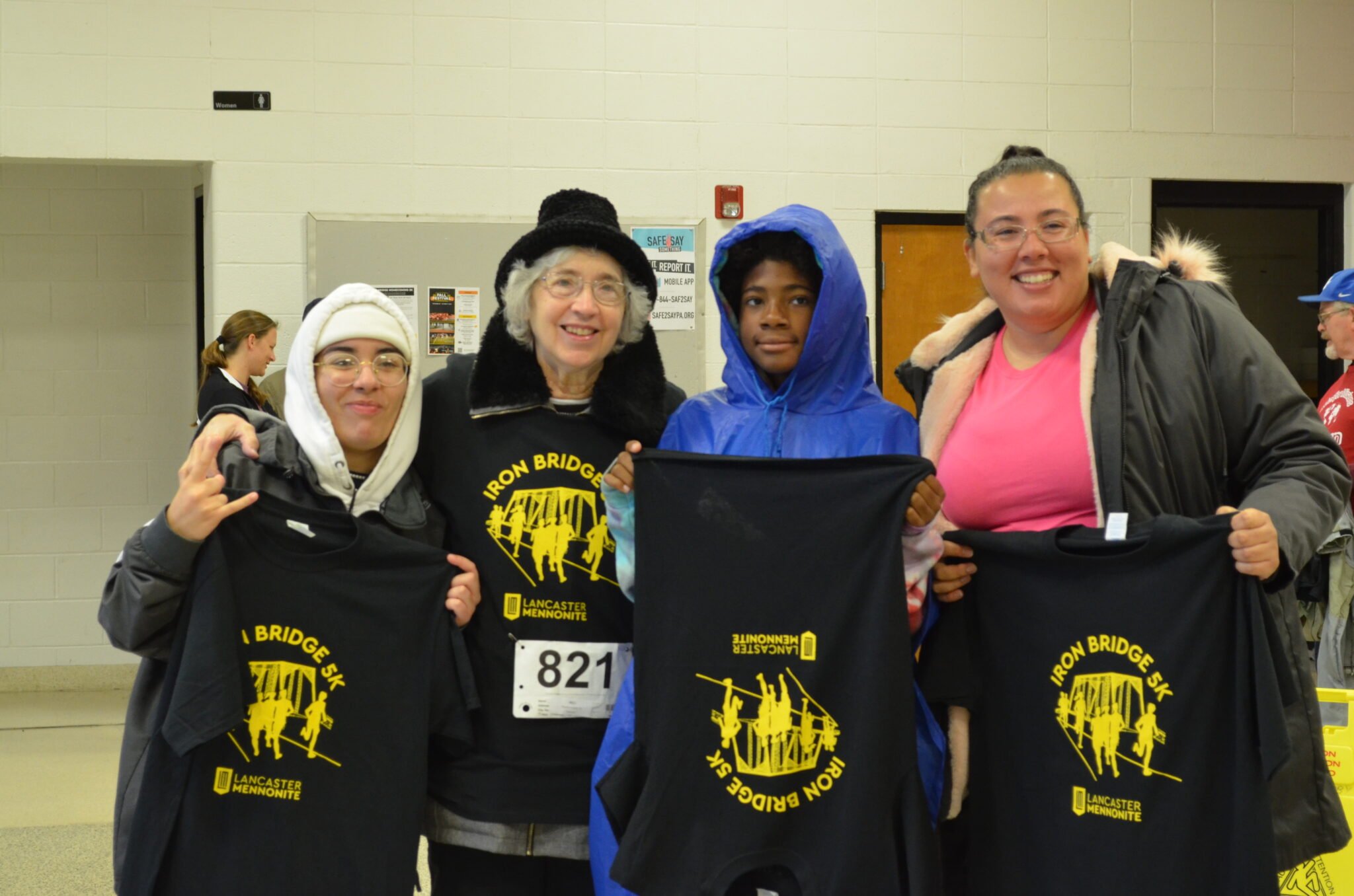 4 people holding up their Iron Bridge Run Shirts