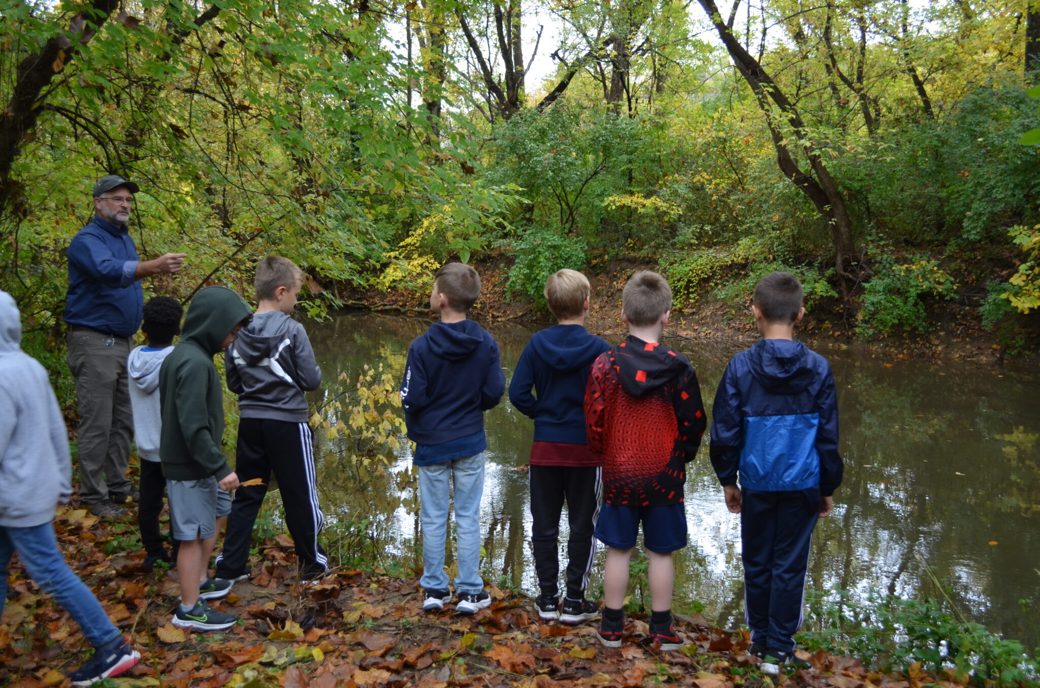 Group of students and Mr. Sauder outside at stream