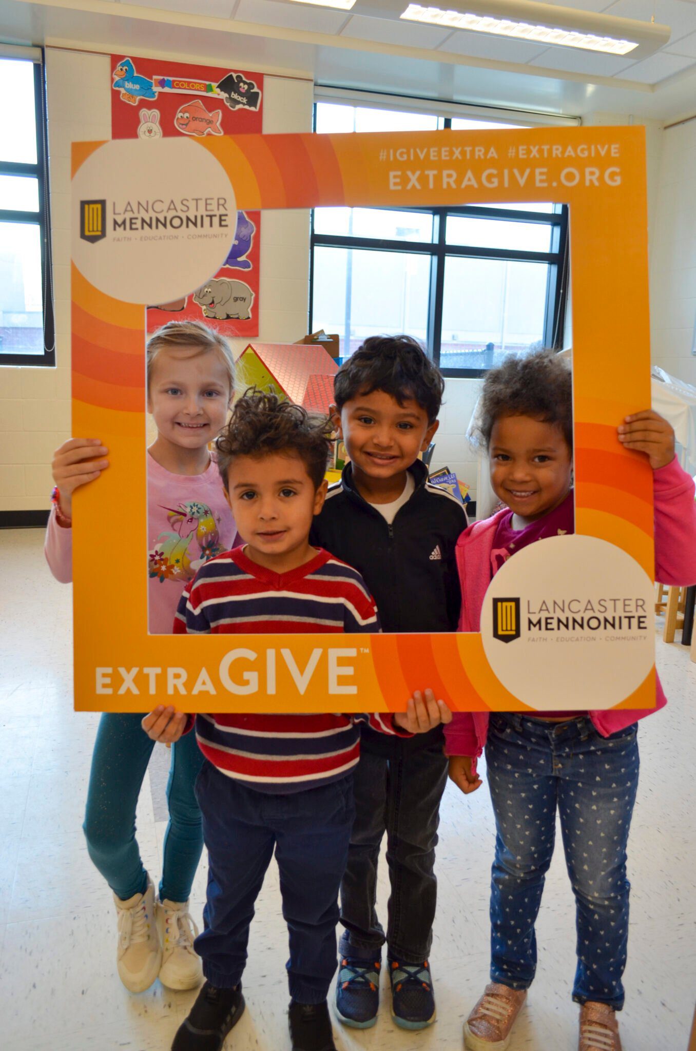 Four elementary students with ExtraGive sign