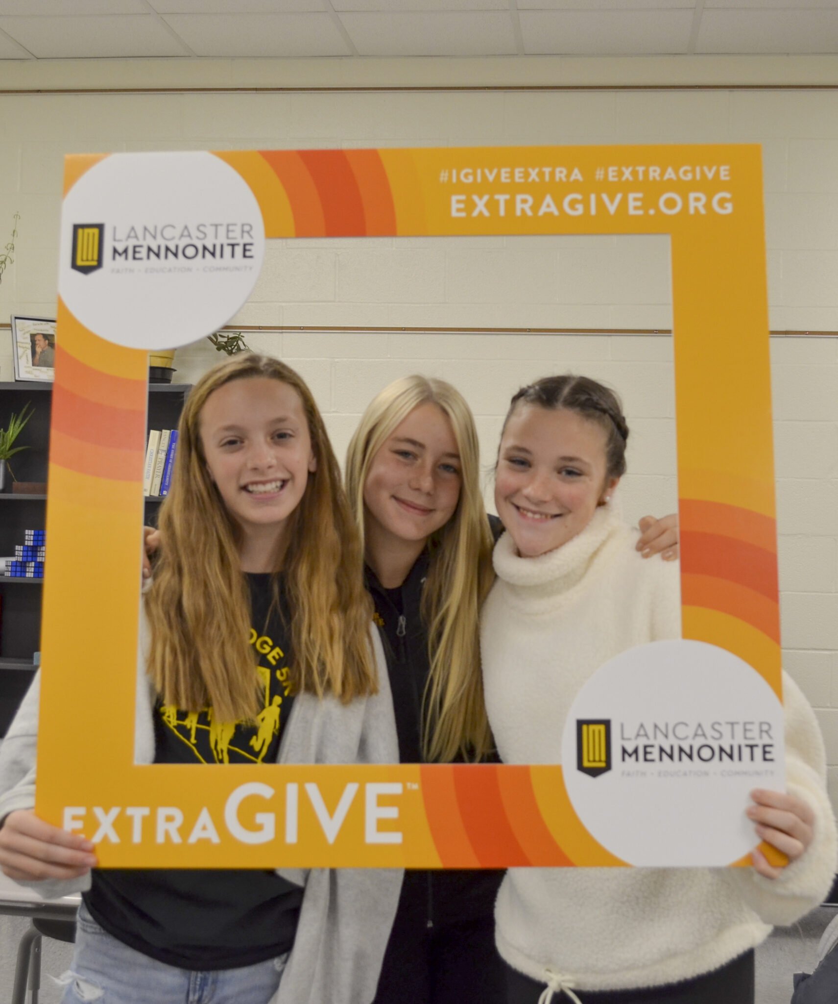 Three Students holding up Extragive sign