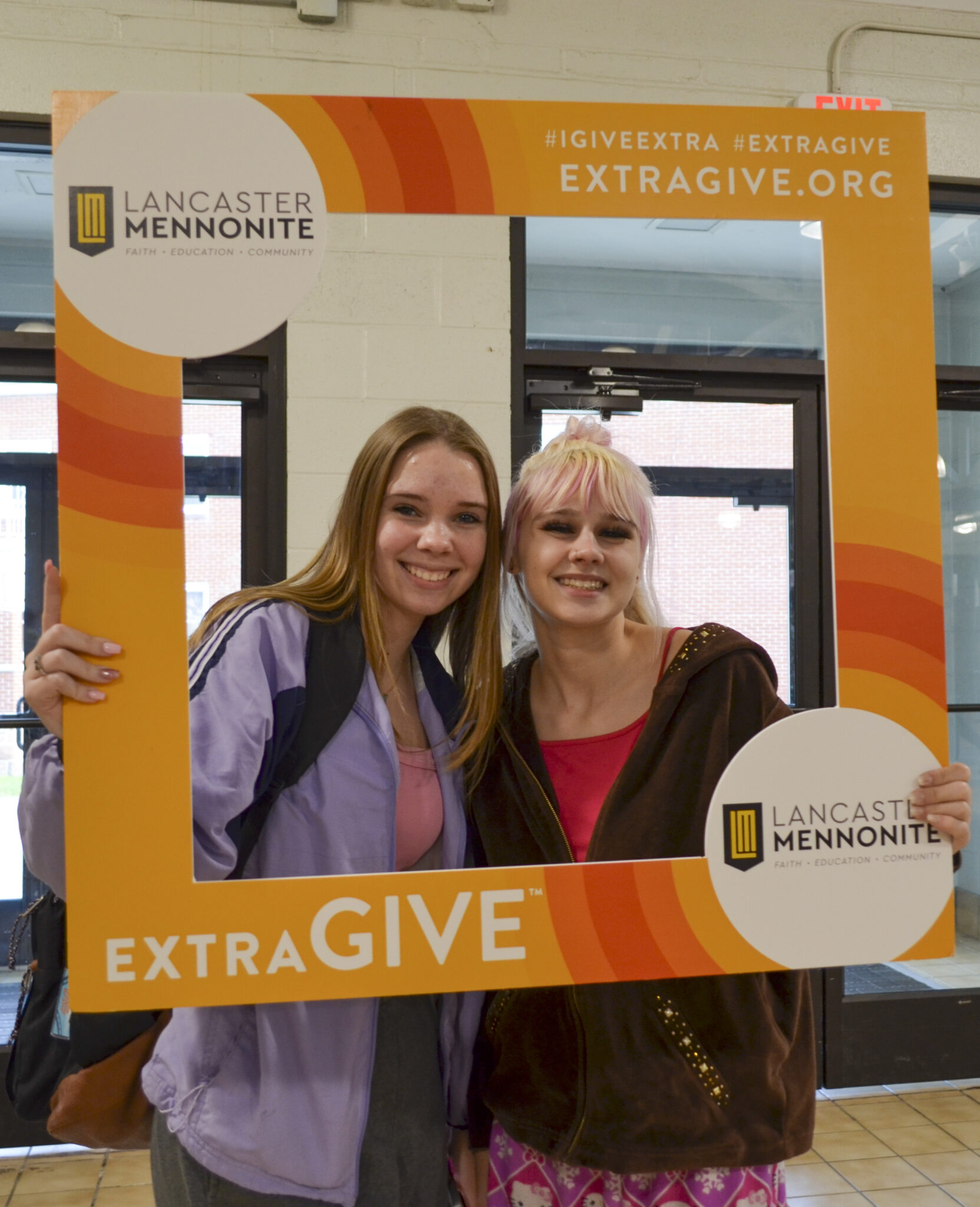 Two LM students holding Extragive Sign