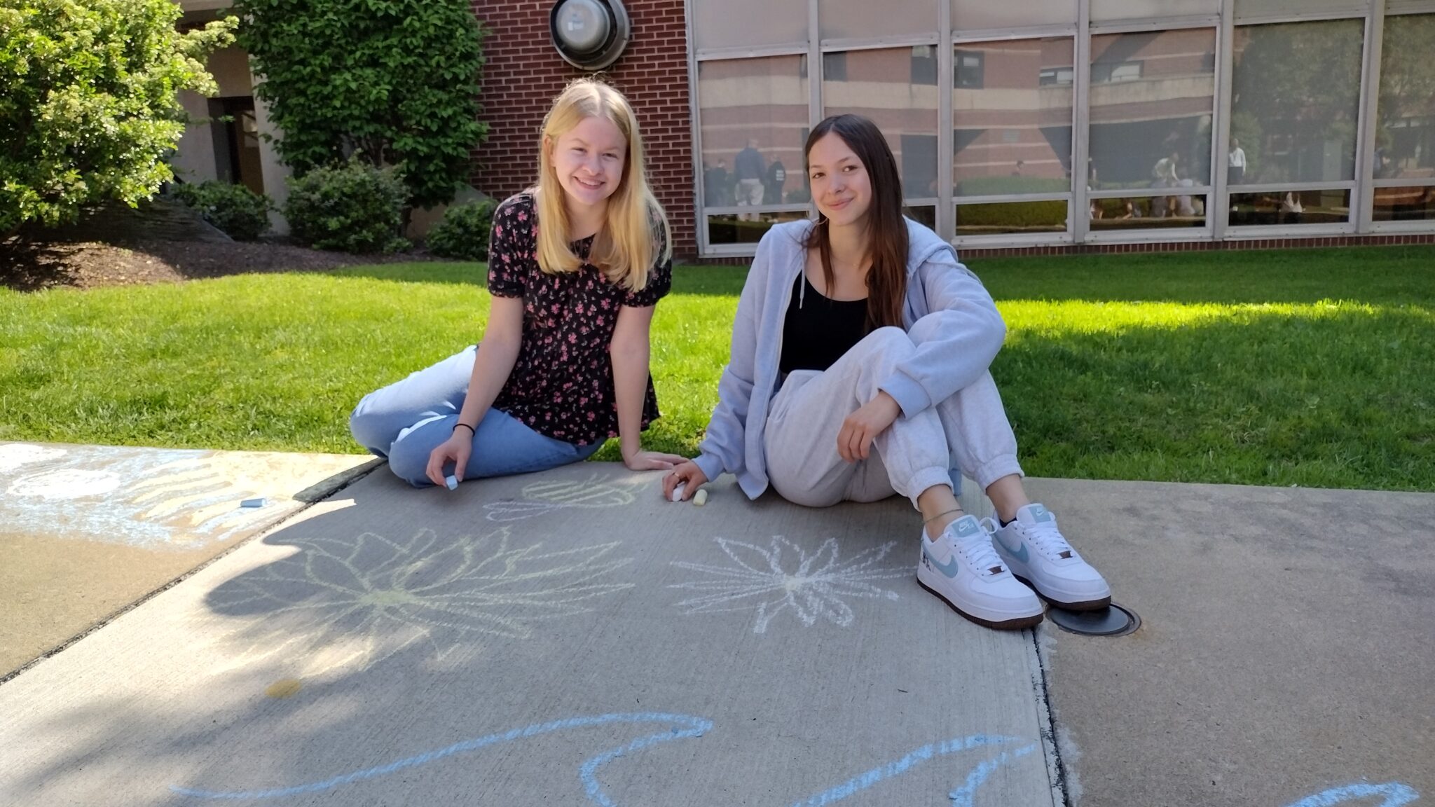 two students drawing on sidewalk