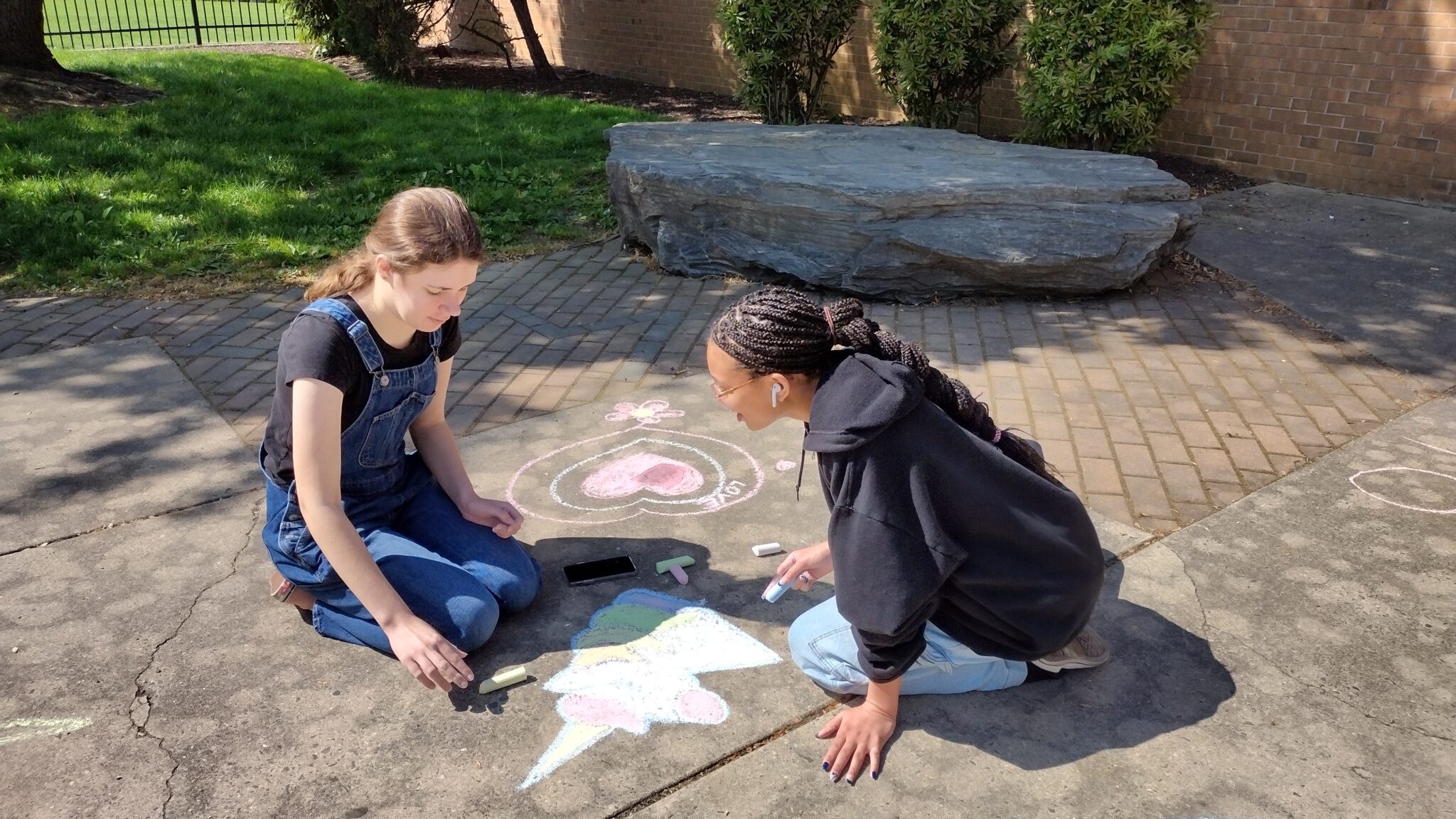 two students drawing on sidewalk