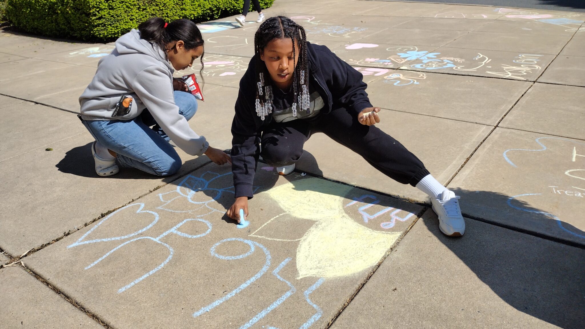 Two students using sidewalk chalk