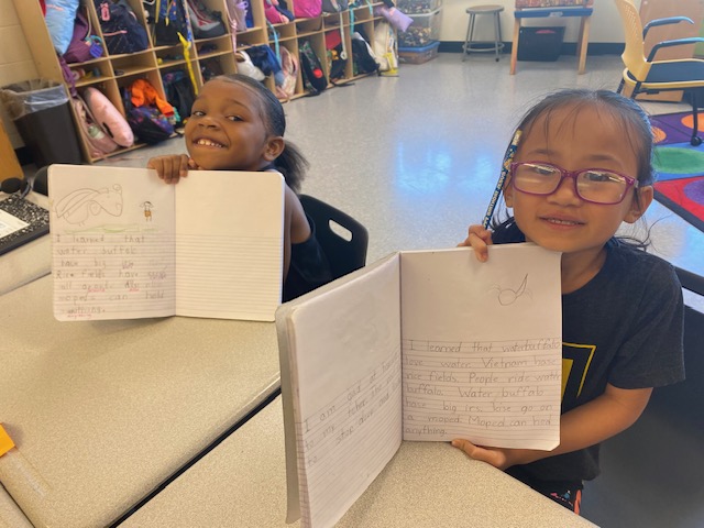 students holding up their workbook