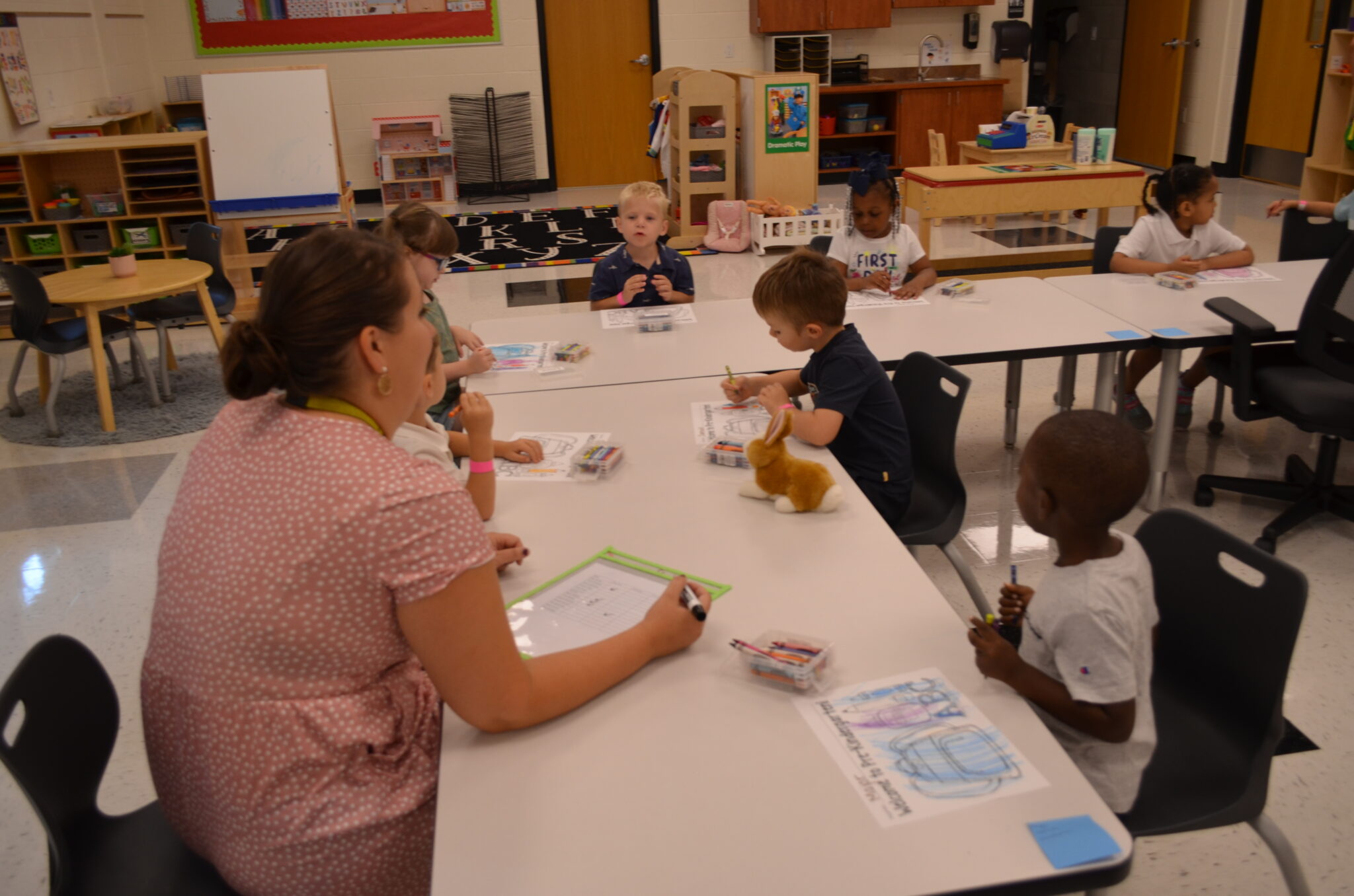 students coloring with teacher