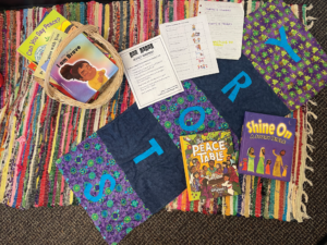 BASKET OF BOOKS IN MRS. CARSON’S OFFICE, COPIES OF RESPECT AGREEMENTS FROM DIFFERENT CLASSROOMS, THE STORY MAT, AND THE TWO MENNOMEDIA STORYBOOK BIBLES USED IN THE CURRICULUM. THE NEW ONE, THE PEACE TABLE, WILL START TO BE INTEGRATED THIS YEAR.