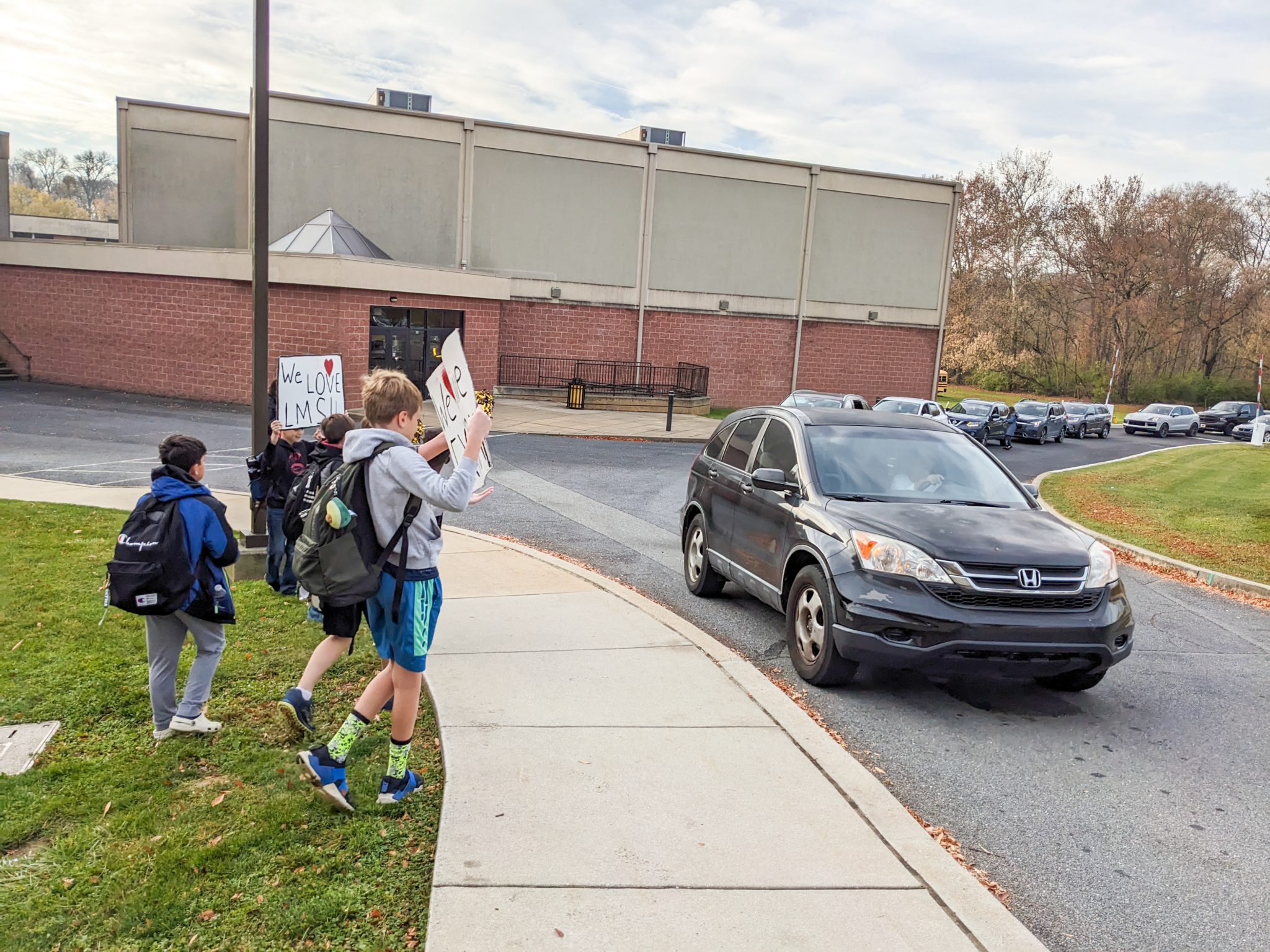 elementary students holding up signs for morning drop off.