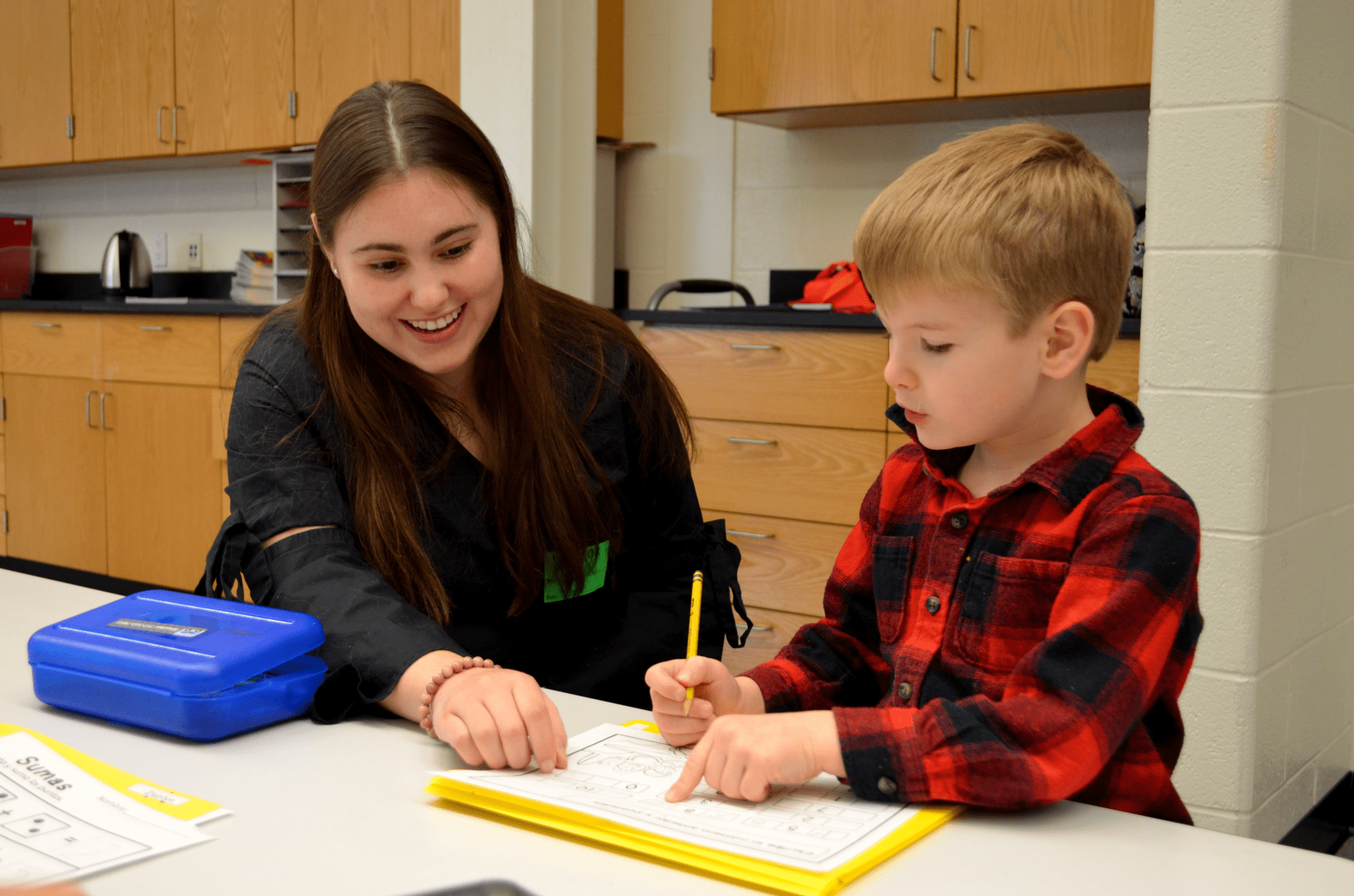 Teacher's Aide working with kindgarten student on worksheet