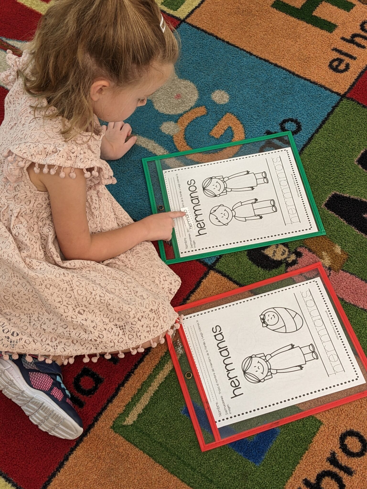 Student learning spanish family words. She is sitting on the floor looking at photos and words of family terms.