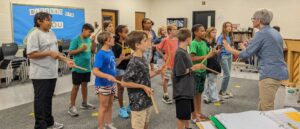 MRS. CARLSON WITH 5-6TH GRADERS LEARNING A SONG - SINGING THE WORDS AND PLAYING RHYTHM STICKS