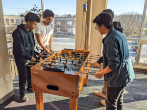 BARKOT (MIDDLE LEFT) PLAYING FOOSBALL IN THE DORM WITH FRIENDS AFTER SCHOOL