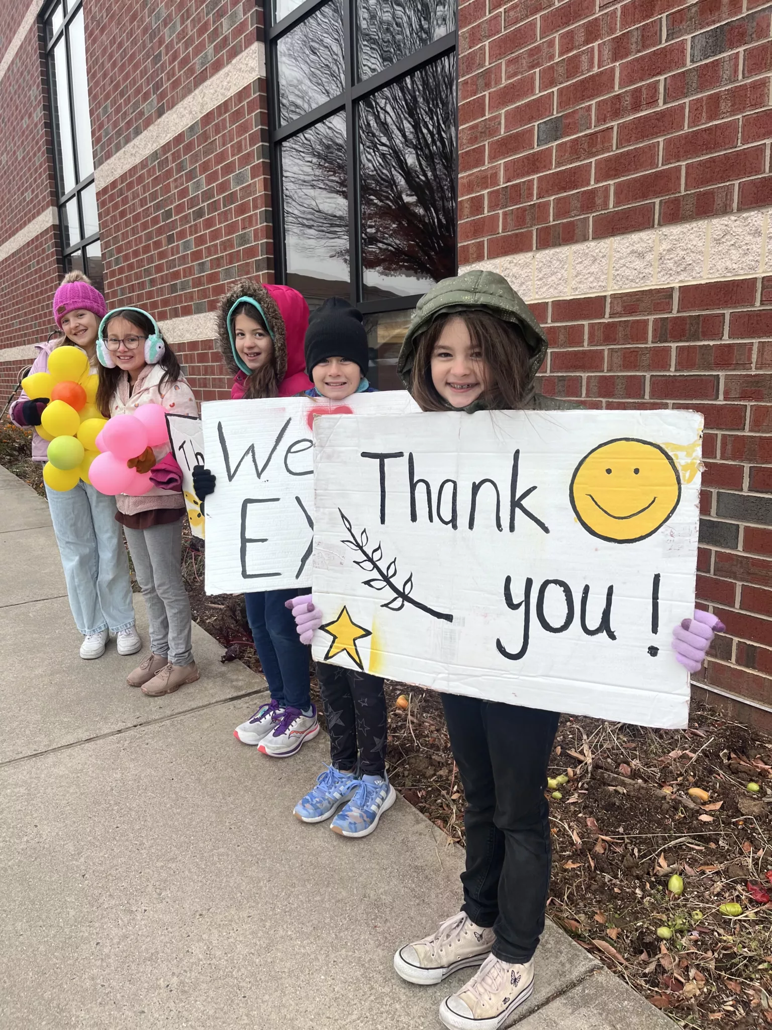 Elementary students holding signs at morning drop off