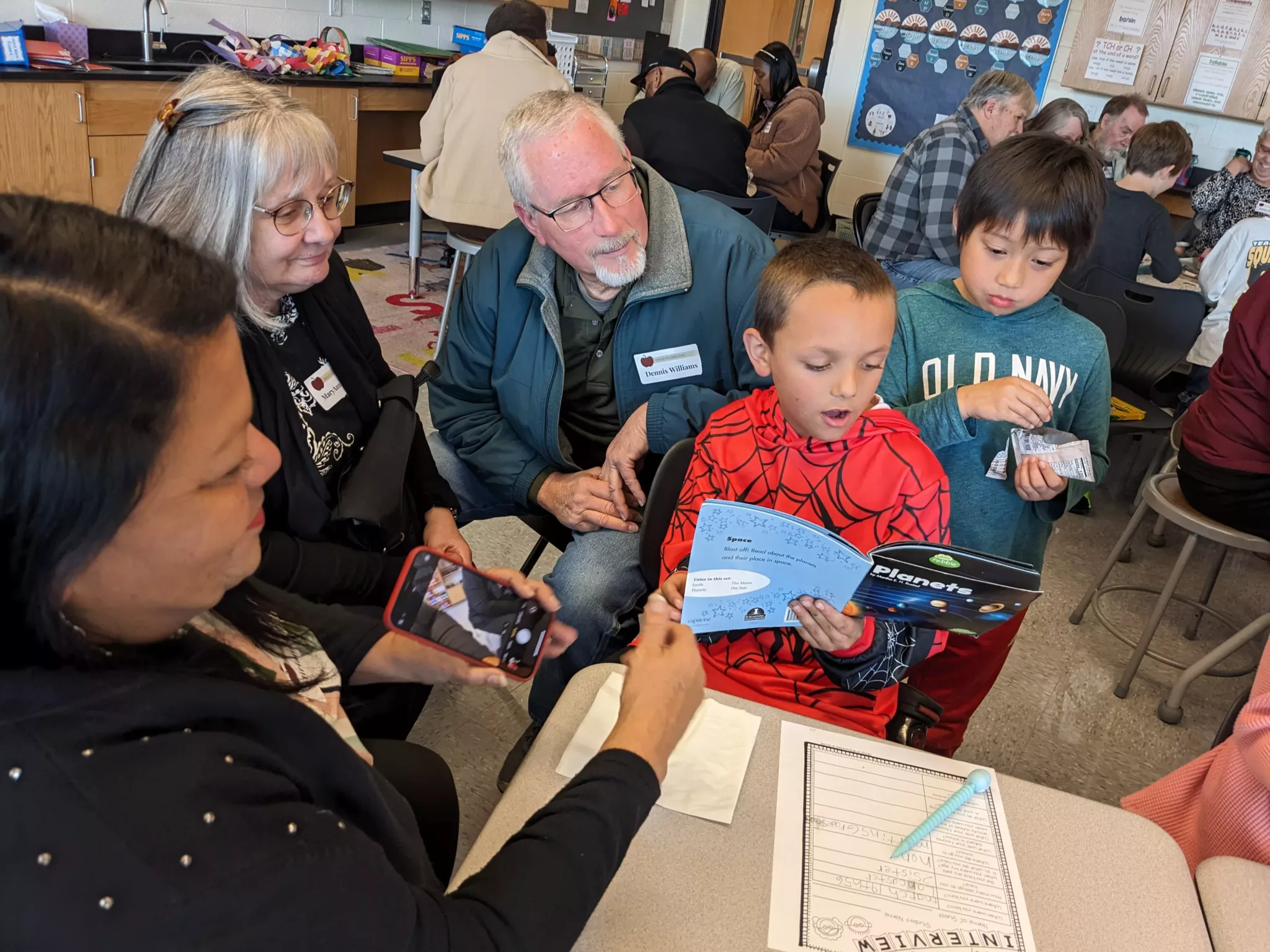 Student with grandparents at Grandparents Day reading a book
